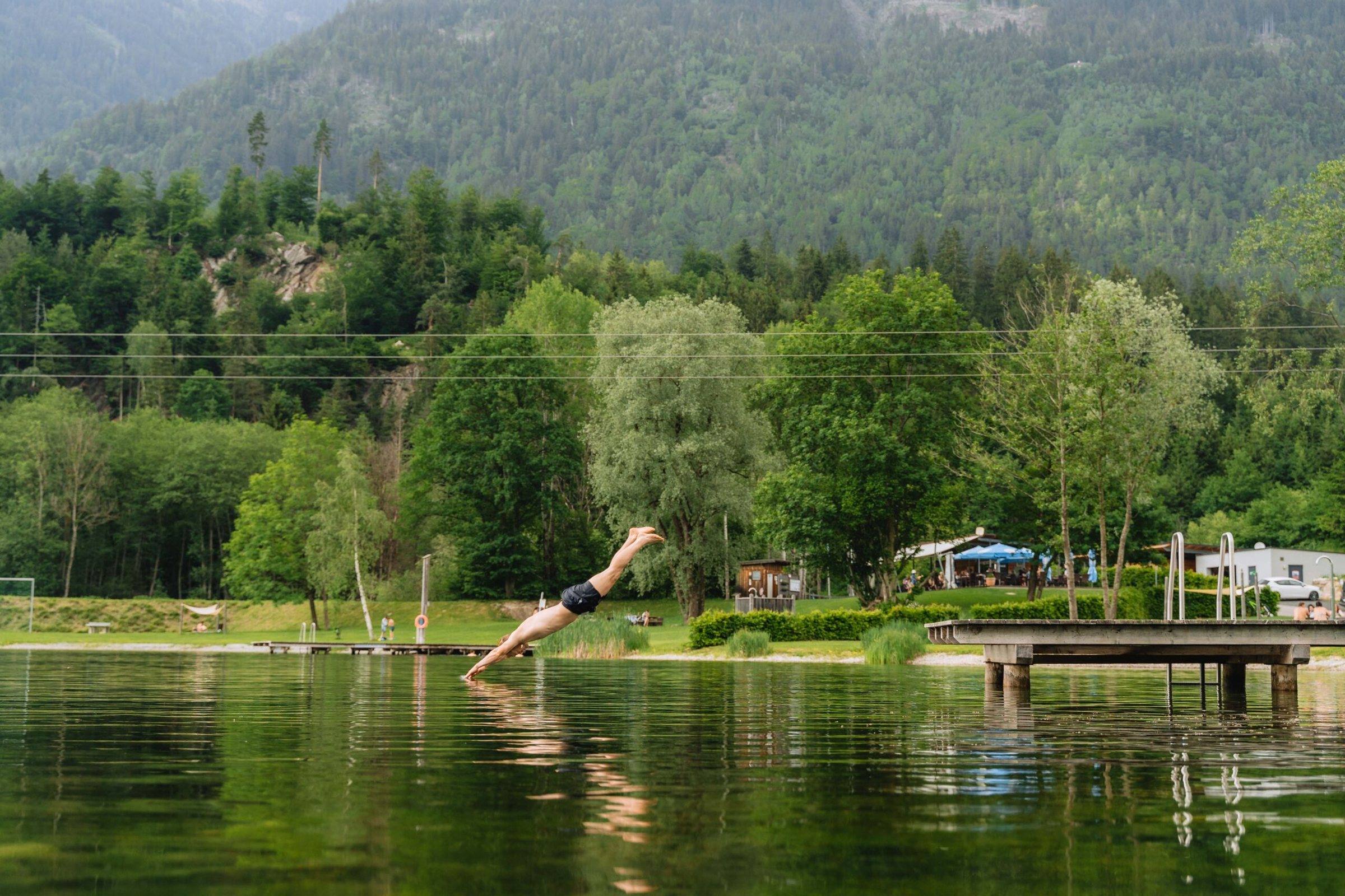 Sprung in den Badesee mit Bergkulisse im Drautal
