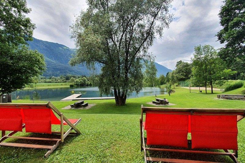 Rote Liegestühle auf der Liegewiese am See