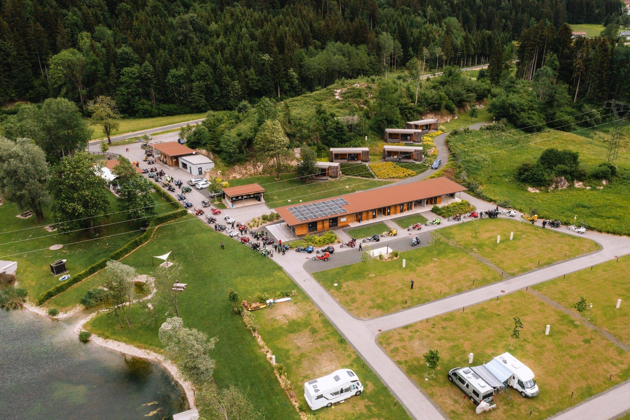 Luftbild des Campingareals mit Wohnmobilen und Badesee
