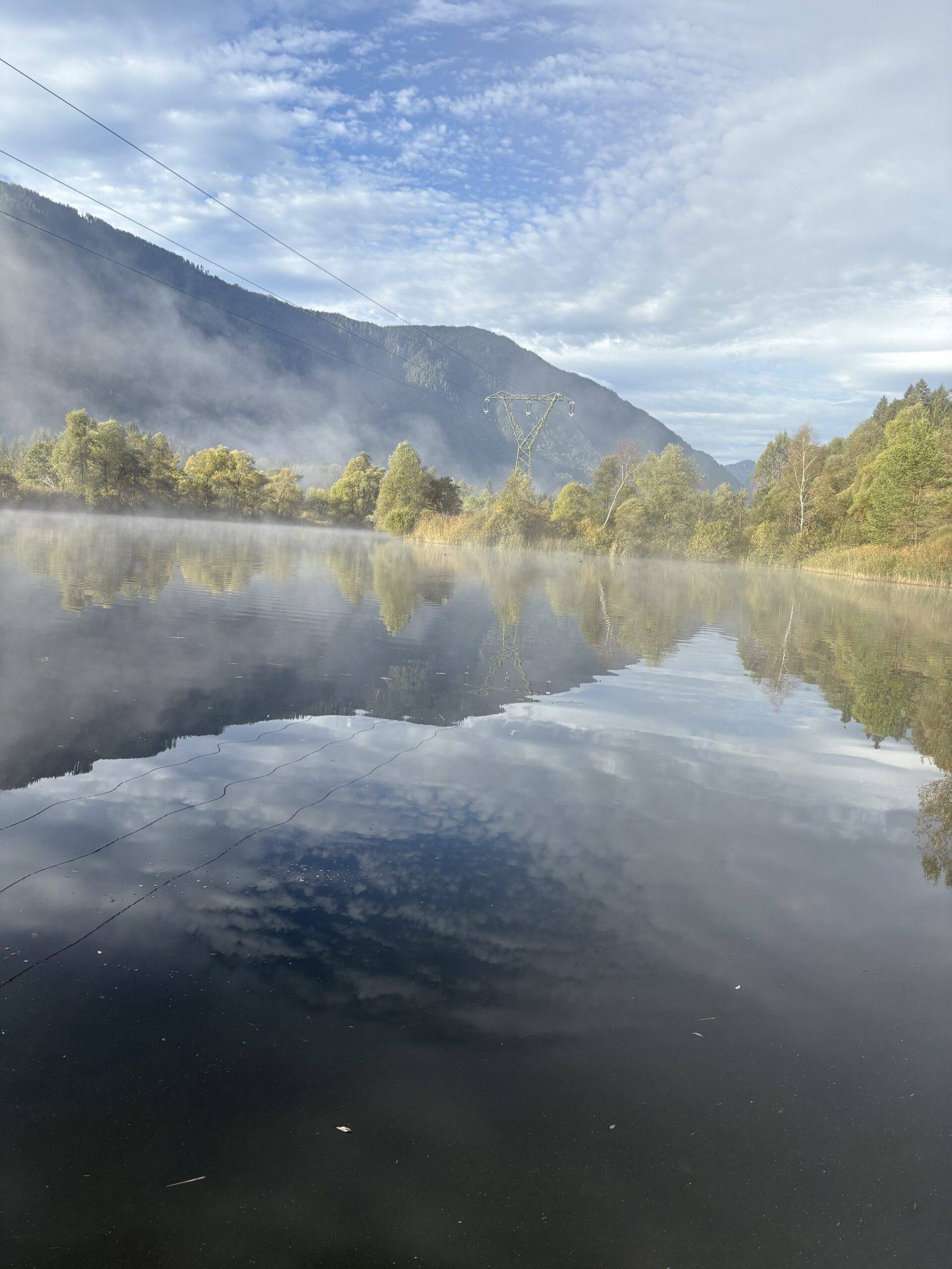 Berge spiegeln sich im ruhigen Badesee